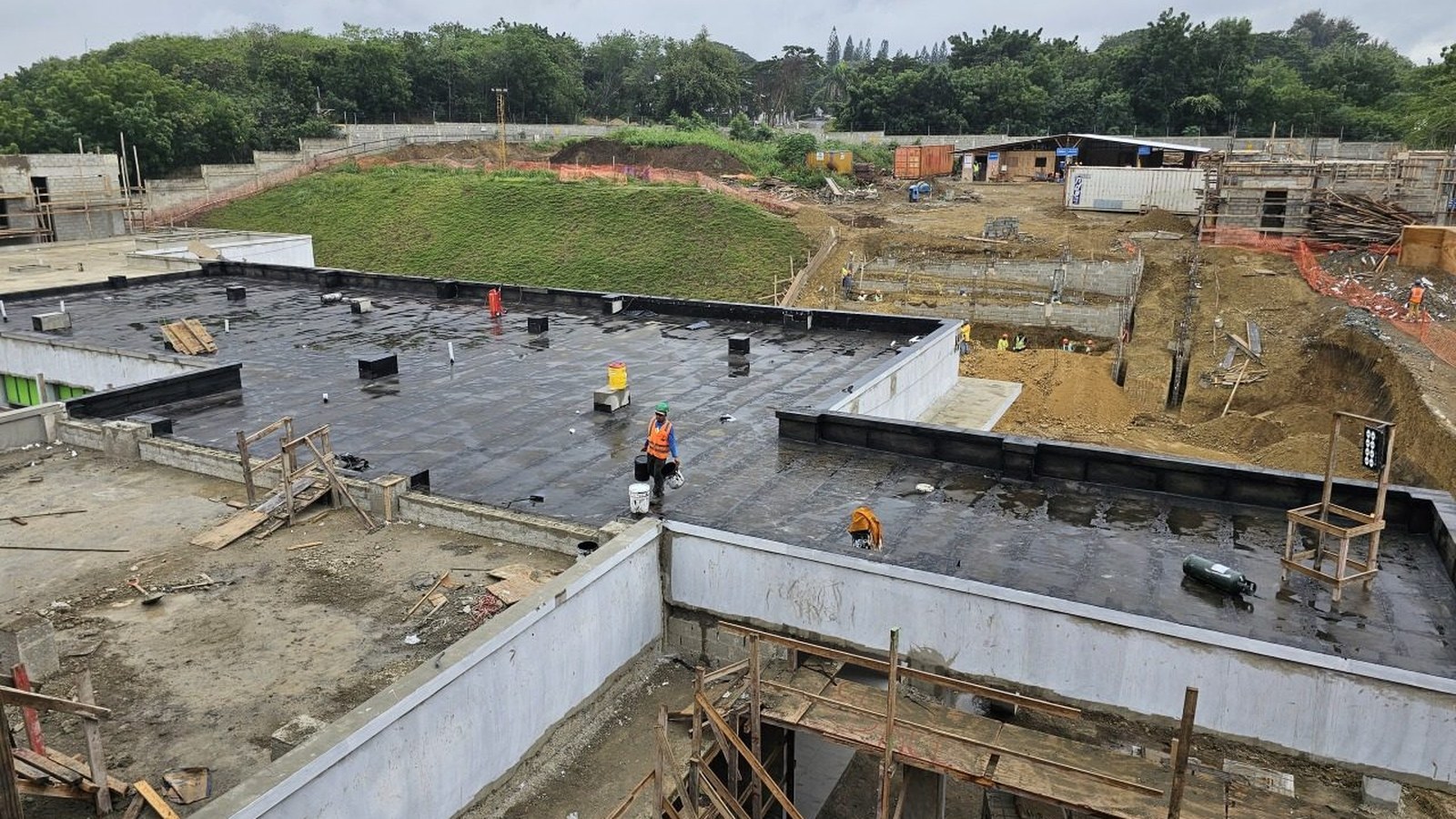 Vista panorámica de obra en construcción con techo impermeabilizado en primer plano