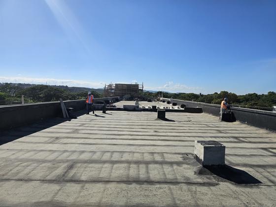 Técnicos de IIECA supervisando techo con membrana asfáltica recién instalada