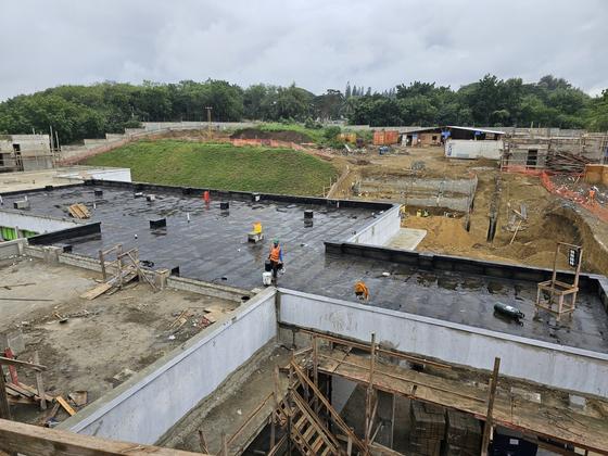 Vista amplia de obra en construcción con sección de techo ya impermeabilizada